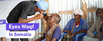 An eye doctor examines a patient at a medical camp in Somalia, with a banner reading "Eyes Waqf.